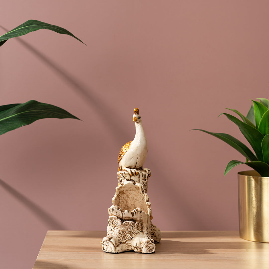 a statue of a bird on a rock next to a potted plant