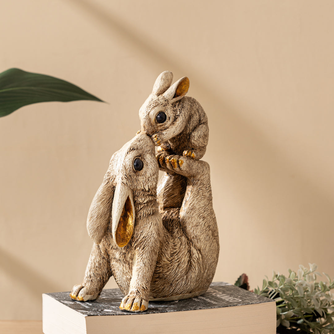 a statue of two rabbits sitting on top of a book