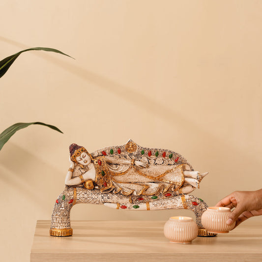 a statue of a buddha sitting on a bench next to a potted plant